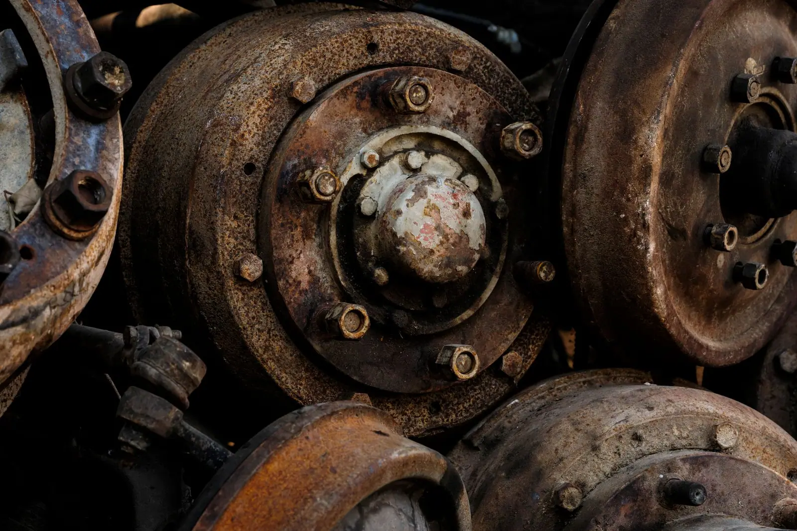 A stack of rusted brake discs and hubs in a scrapyard
