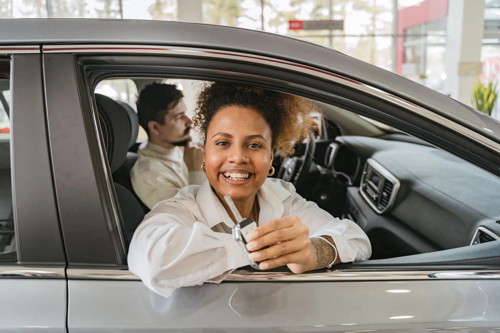 A woman holding a vehicle key while seated in a showroom car