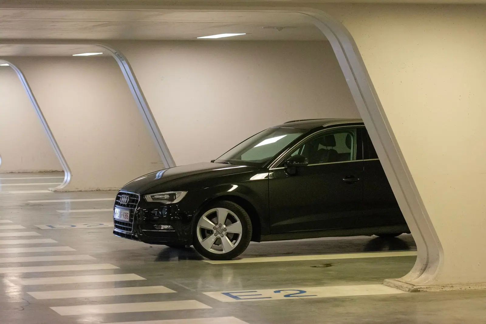 A dark Audi parked in a brightly lit indoor garage